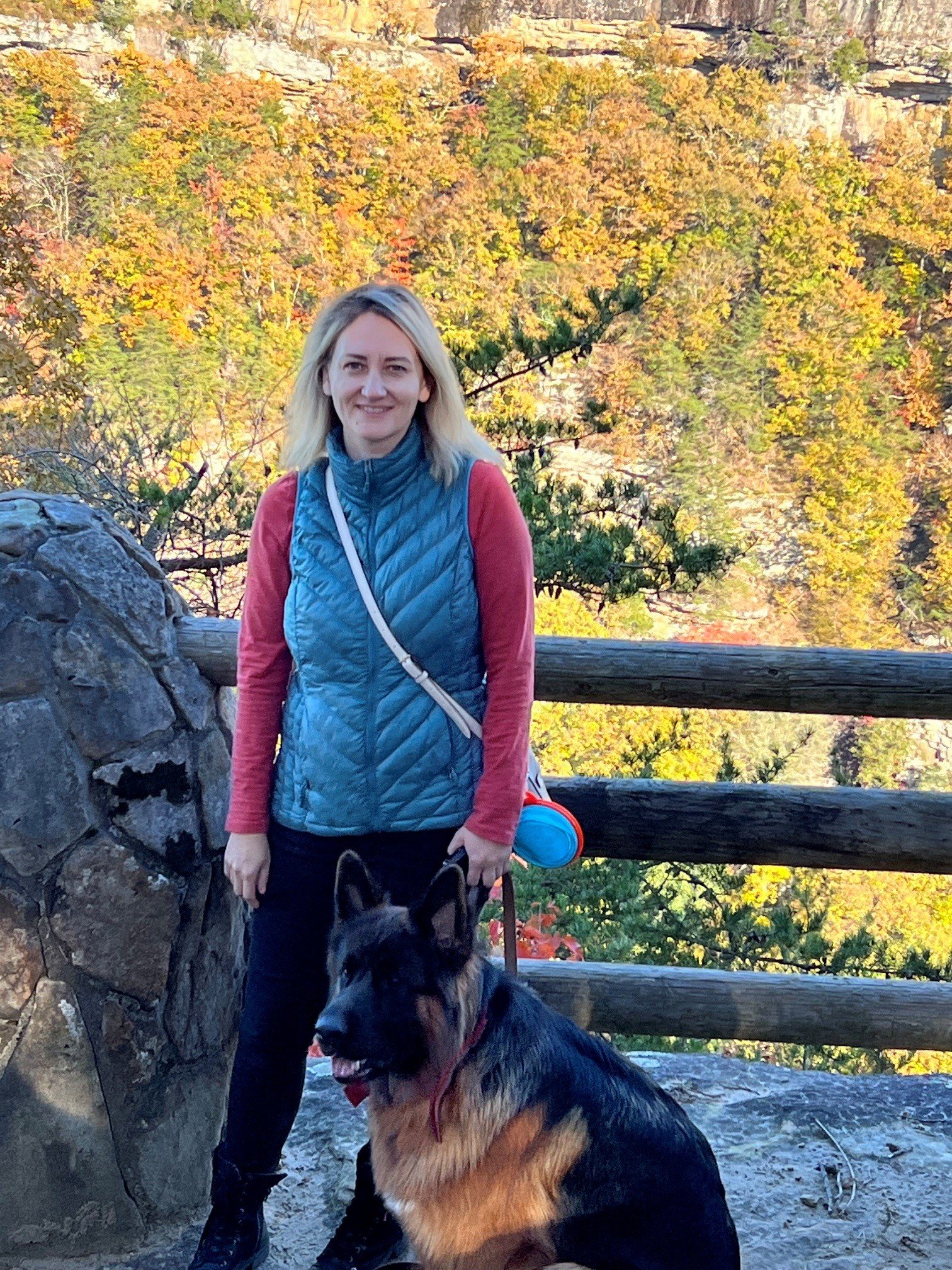 Person standing outdoors beside a German Shepherd