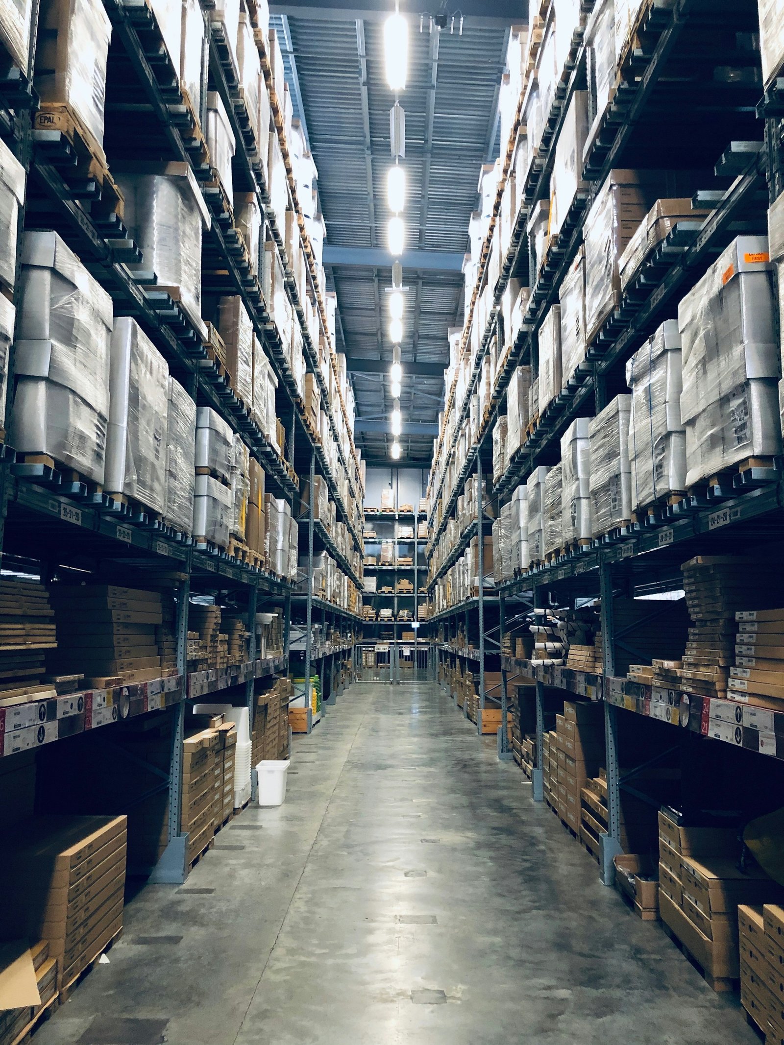 Warehouse aisle with palletized inventory representing wholesale pickup and delivery logistics